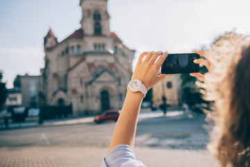 Close-up of young woman traveler making photo of an old church