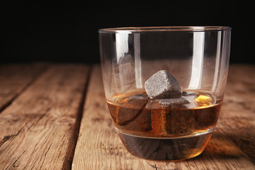 Glass with liquor and whiskey stones on table