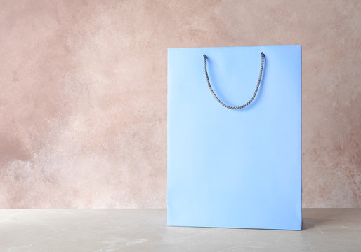 Mockup of paper shopping bag on table against color background