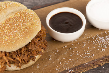 Close up on a pulled pork sandwich and barbecue sauce