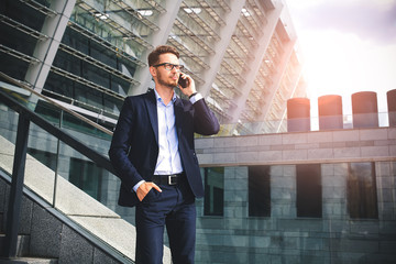 Business man stand at street holding a smartphone in office park