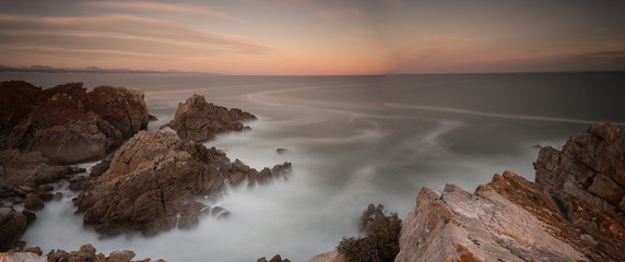 Wide angle landscape image of rock formations and the indian ocean along the Garden Route coast of South Africa