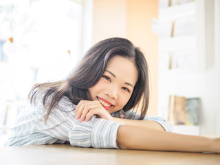 Young Chinese girl sitting in cafe, lying and looking at camera with smile face.