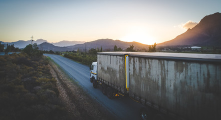 Aerial view of a cargo truck driving of into the sunset