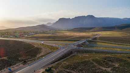 Aerial view over a highway interchange during peak hour traffic.