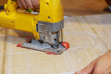 man carpenter builder working with electric jigsaw and wood