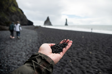 Black rocks on hand from black sand beach Reynisfjara Vik ,Iceland.