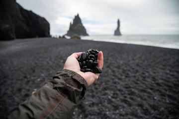 Black rocks on hand from black sand beach Reynisfjara Vik ,Iceland.