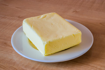 Butter on a white plate on a wooden table.