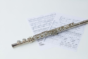 白背景の上の楽譜とフルートの写真 © 健二 中村