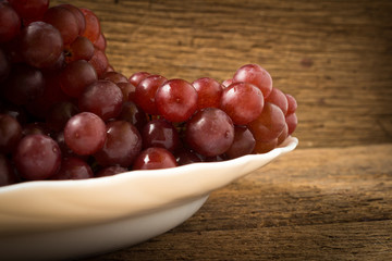 grapes seedless red on dish on old wood