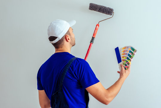 Uniform man choosing right color for painting wall in living room. home improvement concept.
