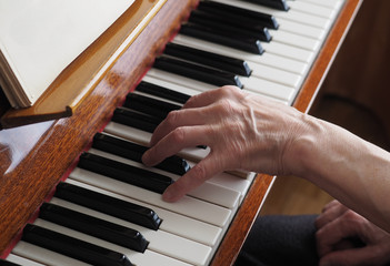Elderly woman hands playing the piano, close up