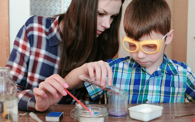 Chemistry experiments at home. Boy pours water from the test tube into the flask using.