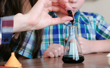 Chemistry experiments at home. Woman dripping the paint into the flask with the liquid.