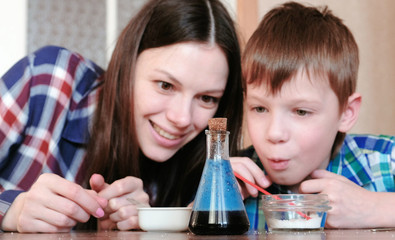 Chemistry experiments at home. Surprised Mom and son make a chemical reaction with the release of gas in the flask.