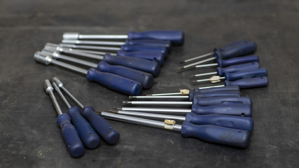 Different types of screwdrivers on the workbench, blurred background 