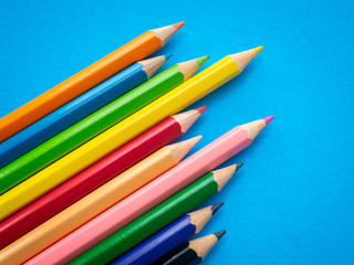 Closeup color pencils isolated on blue paper background. Education, Back to school Concept.
