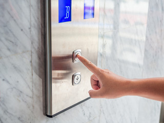 Naklejka premium Close up man hand press a up button of elevator inside the building for upper high level floor.