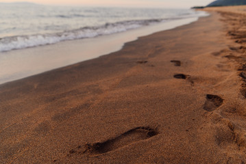 footprints of the girl on the sand, the shore of lake Baikal. Sunset, clean sand, water.