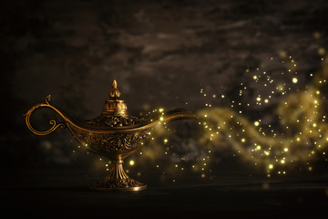 Image of magical mysterious aladdin lamp with glitter sparkle smoke over black background. Lamp of...