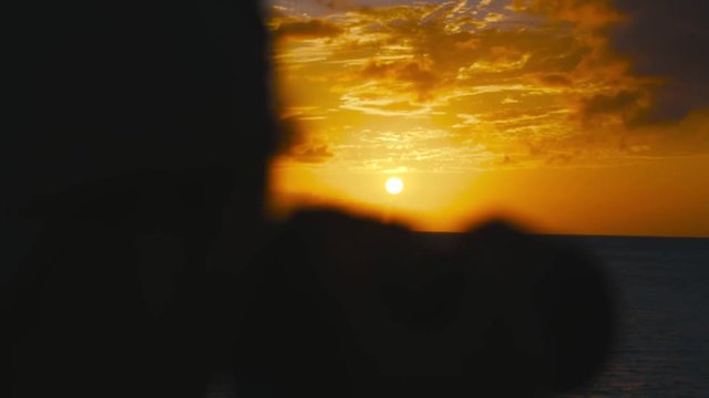Silhouette of boy taking pictures during sunset, Curacao