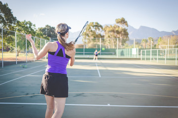 Close up image of a female tennis player playing tennis on a court in bright sunlight