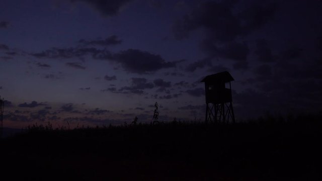 Hunting tower, hide, lookout in dusk with cloudscape, clouds moving on dramatic sky