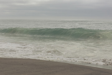 Small ocean waves, Overcast sky. Hazy background.