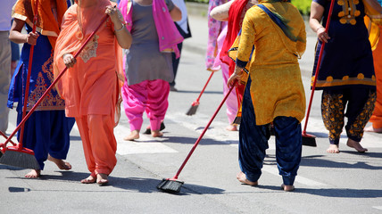 barefoot women clean the street with brooms at a Sikh religious