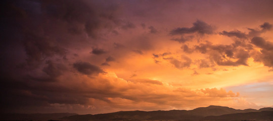 Fototapeta na wymiar Red cloudy sky at sunset, mountain range, banner, copy space, wallpaper.