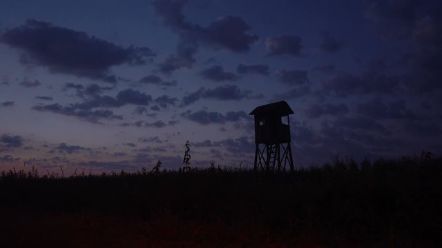 Hunting tower, hide, lookout in dusk with cloudscape, time lapse of clouds moving on dramatic sky