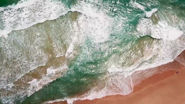 Aerial view of sand beach. Looping ocean texture, Top view sea waves slow motion, flying over tropical sandy beach and waves, Sunset beach seamles loop.