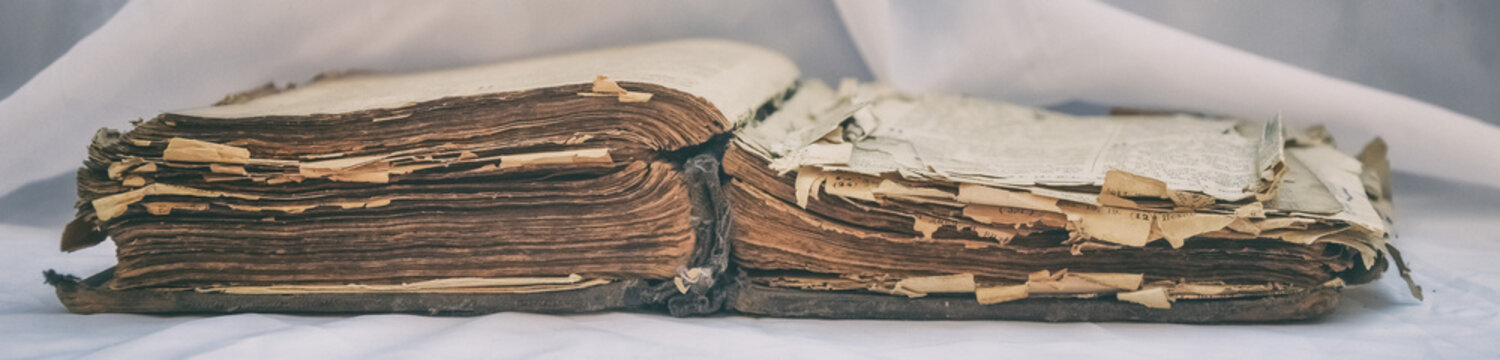 The old antique scruffy book "Bible" lies open on the table with white drapery. The concept of the teachings of Jesus.