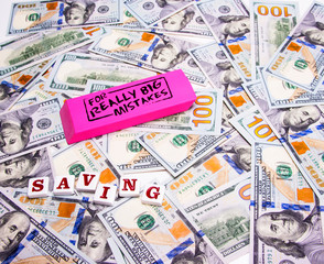 Scattered US dollars with message on pink eraser for big mistakes and savings. Concept fixing financial, business, taxes, savings, loan mistakes