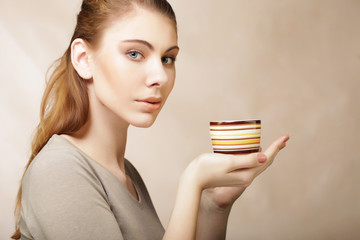 portrait of a beautiful woman with a cup of coffee standing on the beige background