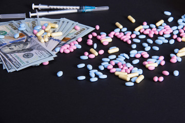 Fototapeta na wymiar The expenses of medications. Scattered pills next to syringe and hundred dollar bills