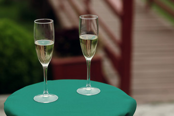 luxury glasses of champagne on green table at wedding outdoor reception and ceremony. catering in restaurant. celebration drinks. space for text