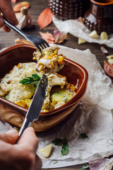 Baked potatoes with meat dipped in cheese in clay brown dishes on a wooden background