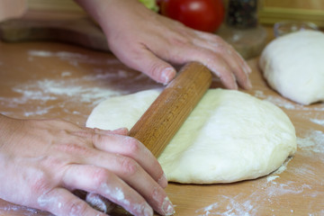 Woman pressing dough with rolling pin. She preparing pizza