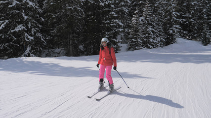 Fototapeta na wymiar Sporty young woman skis down the slope in the mountains of the Alps