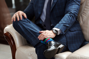 Young man in elegant suit sitting on sofa indoors