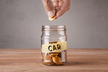 Car. Glass jar with coins and an inscription car. Man holds coin in hand