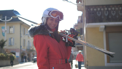 Attractive Woman Stands Near Houses Holding Her Downhill Ski Before Skiing