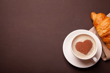 Cup of coffee with heart on the foam. I like morning coffee with croissant