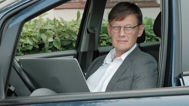 Mature businessman in car working on laptop