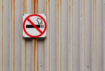 sign no smoking hangs on a rusty gray metal surface