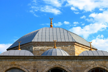 Fototapeta na wymiar Roof and domes of an ancient mosque against a blue sky with clouds