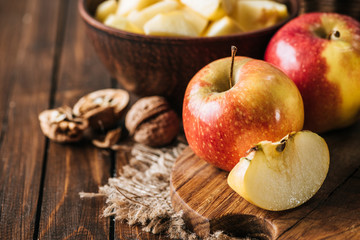close up view of fresh apples and hazelnuts on cutting board on wooden surface
