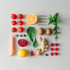 Kreatives, übersichtliches Essenslayout mit Obst, Gemüse und Blättern auf hellem Hintergrund. Minimales Konzept für gesunde Ernährung. Flach liegen.